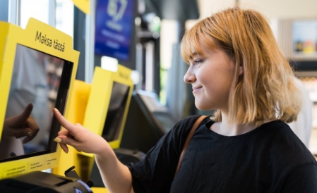 Nuori henkilö näppäilee R-kioskin pikakassan näyttöä.